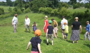 Photo of a group of people, young and old, walking in the countryside.